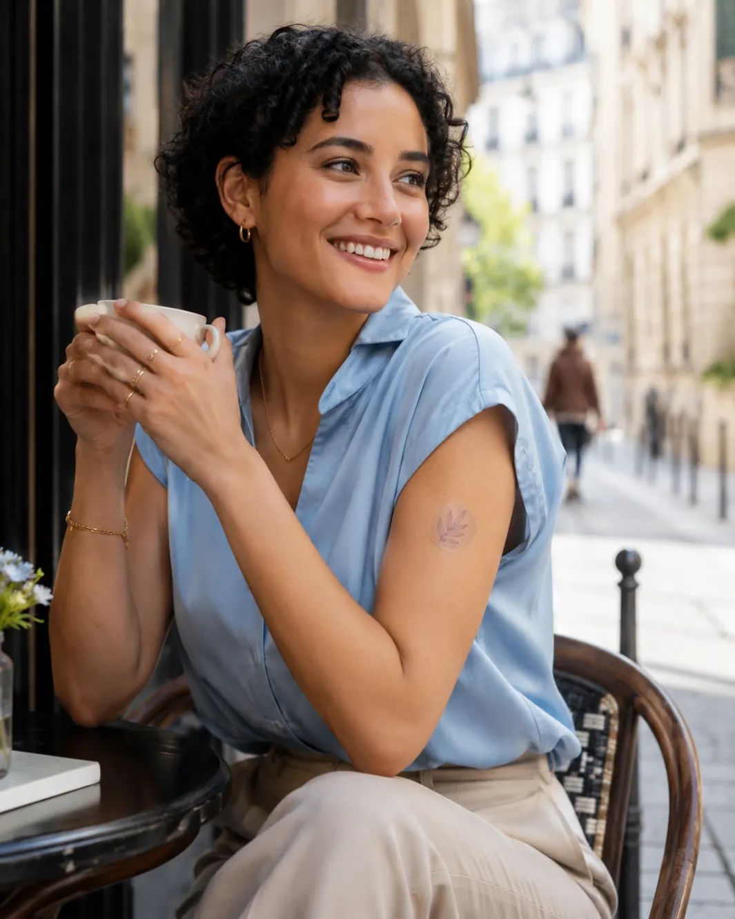 Woman at a Parisian café with an AuraVita patch on her arm
